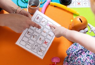 Adult and child pointing to alternative communication device